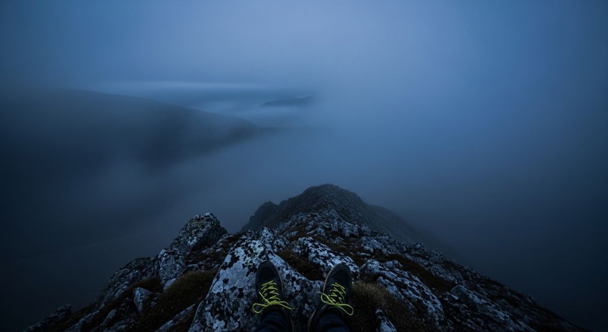 A view from a mountain summit into thick indigo mist.